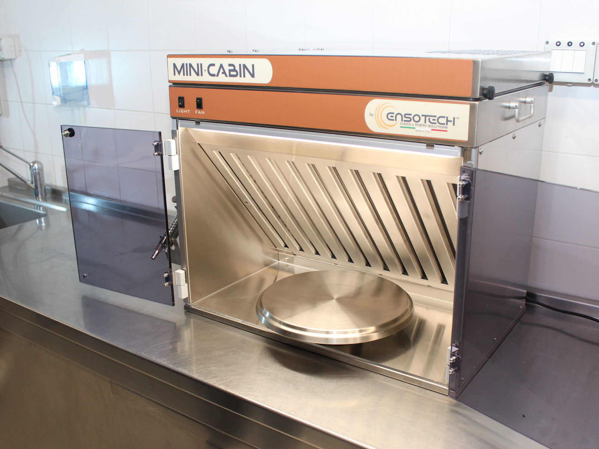 Mini Cabin Ensotech su banco inox con piatto girevole: cabina di aspirazione compatta per decorazioni di cioccolato e pasticceria.