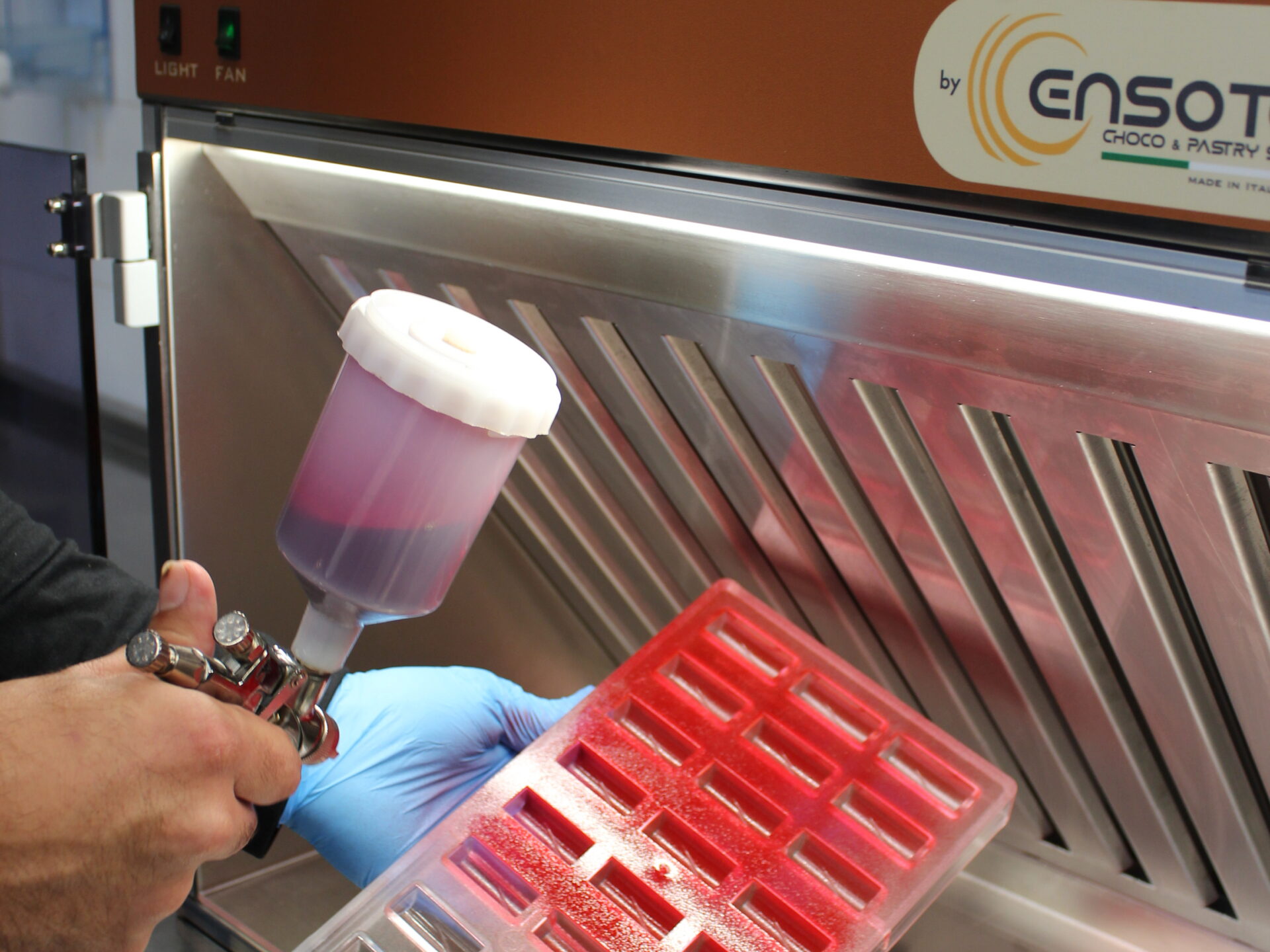 Decorazione stampo per cioccolato con aerografo nella Mini Cabin Ensotech, cabina di aspirazione compatta per pasticceria.